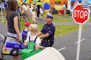 policjant z dziećmi na terenie miasteczka ruchu drogowego