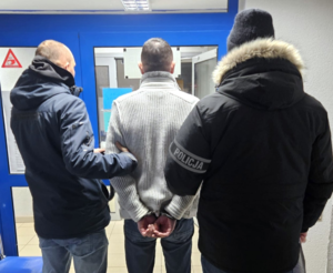 dwaj mężczyźni prowadza mężczyznę w kurtce