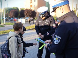 zdjęcie kolorowe: policjanci rozdają dzieciom kaski i elementy odblaskowe