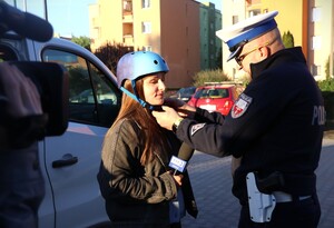 zdjęcie kolorowe: policjanci rozdają dzieciom kaski i elementy odblaskowe