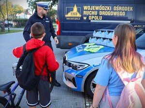 zdjęcie kolorowe: policjanci rozdają dzieciom kaski i elementy odblaskowe