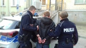 Policjant i policjantka prowadzą zatrzymanego