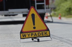 trójkąt ostrzegawczy oraz napis wypadek ustawione na drodze