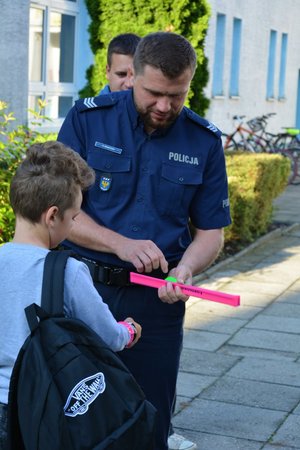Policjanci rozdają elementy odblaskowe i rozmawiają o bezpieczeństwie z uczniami