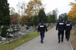 trzech policjantów idzie aleją cmentarną
