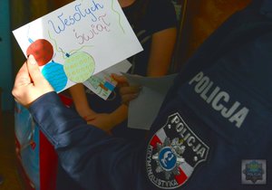 policjantka w dłoni trzyma kartę z napisem &quot;wesołych świąt&quot;