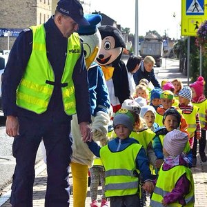 policjant prowadzi dzieci za ręce