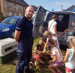 policjant obok pies i 3 dzieci psa głaszczą
