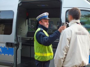 policjant przeprowadza badanie na zawartość alkoholu