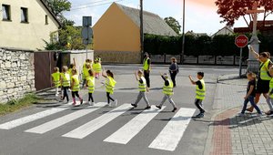 policjant przeprowadza dzieci w odblaskach przez jezdnię