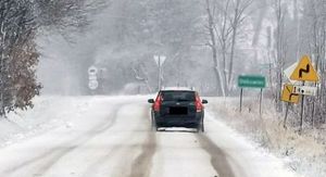 samochód jadący przez zaśnieżoną drogę