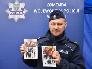 policjant trzyma 2 książki w dłoniach
