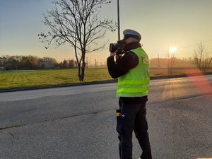 policjant przy drodze mierzy prędkość kierowców
