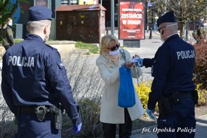 policjanci wręczają maseczkę kobiecie na ulicy