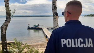 policjant odwrócony plecami patrzy na jezioro