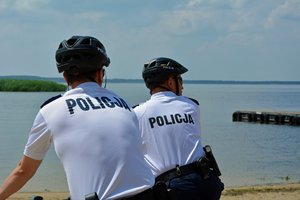 policjanci na rowerach kontrolują plaże przy jeziorze
