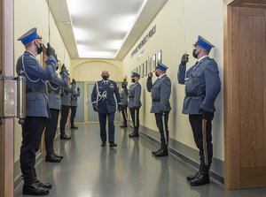 generał idzie korytarzem po bokach policjanci z pocztu sztandarowego salutują