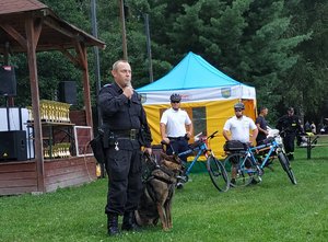 na wprost stoi policjant z psem z tyłu policjanci z rowerami
