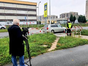 policjant stoi przy przejściu dla pieszych i jest filmowany przez operatora kamery